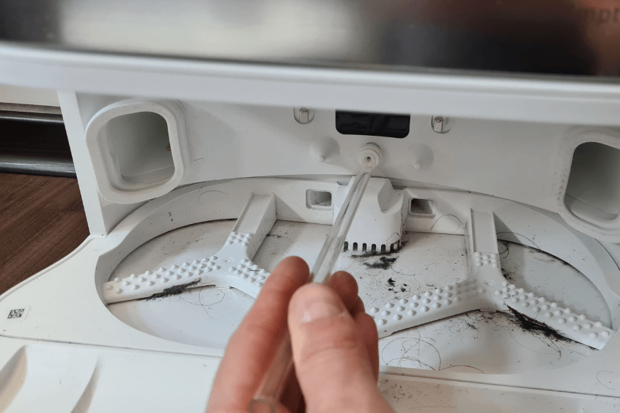  A glass straw is held on the water outlet of the Dreame L10s Ultra base station.